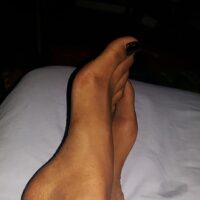 Pieds de femme à Nanterre vernis noirs posés sur lit pour fétichiste soumis